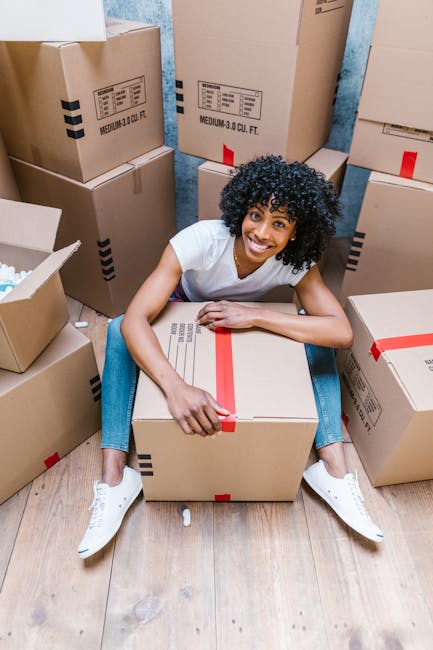 Close-up of several cardboard boxes used for home relocation, with one box labeled 'STUFF' and a small smiley face drawn beneath the text, and another box labeled 'CLOTHES' placed directly below it. T